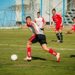 Athletes compete in a lively soccer match on a sunny day in Mendoza, Argentina.