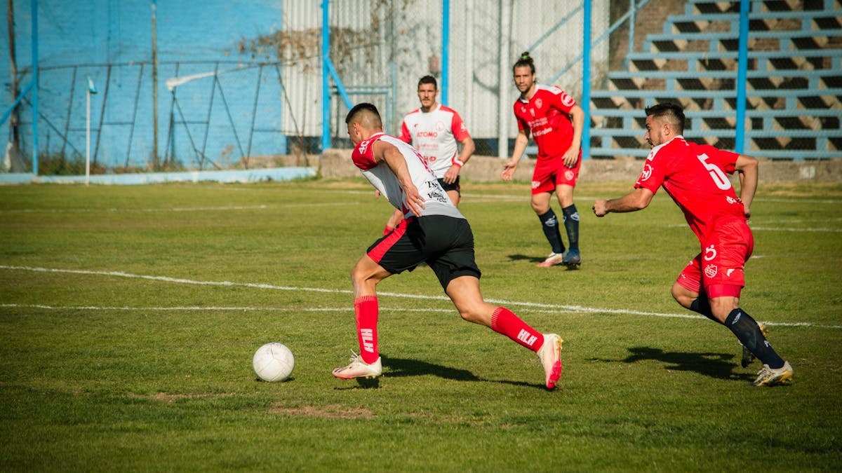 Athletes compete in a lively soccer match on a sunny day in Mendoza, Argentina.