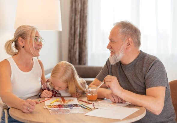 Grandparents and a child bond over painting at a cozy home setting, smiling and focused.