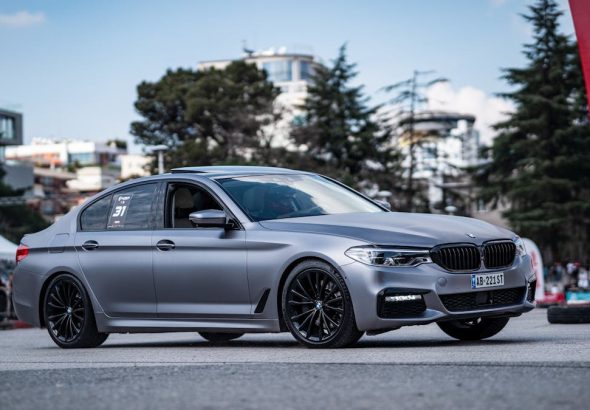 A stylish silver BMW parked on a city street during a car event, showcasing modern design.